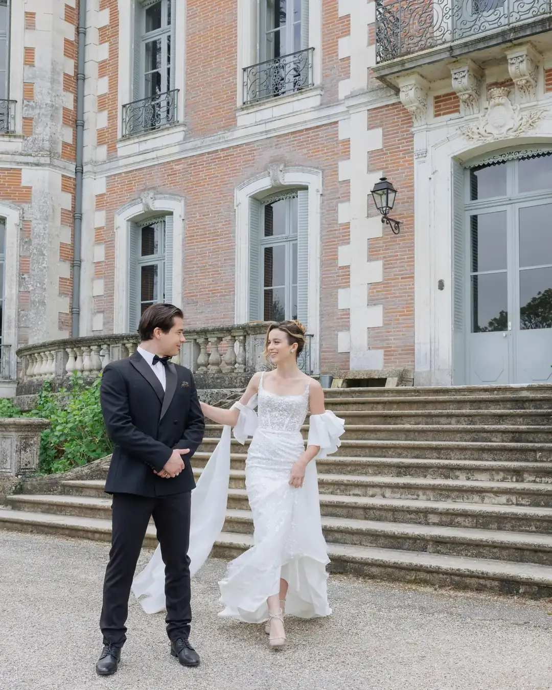 Les mariés descendent l'escalier d'un château de brique en Occitanie