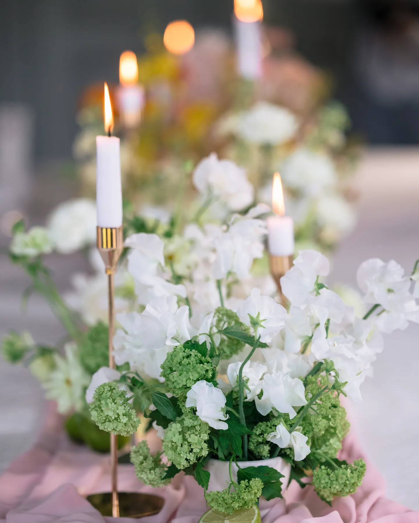 Centre de table fleuri éclairé à la bougie, tons blanc et vert
