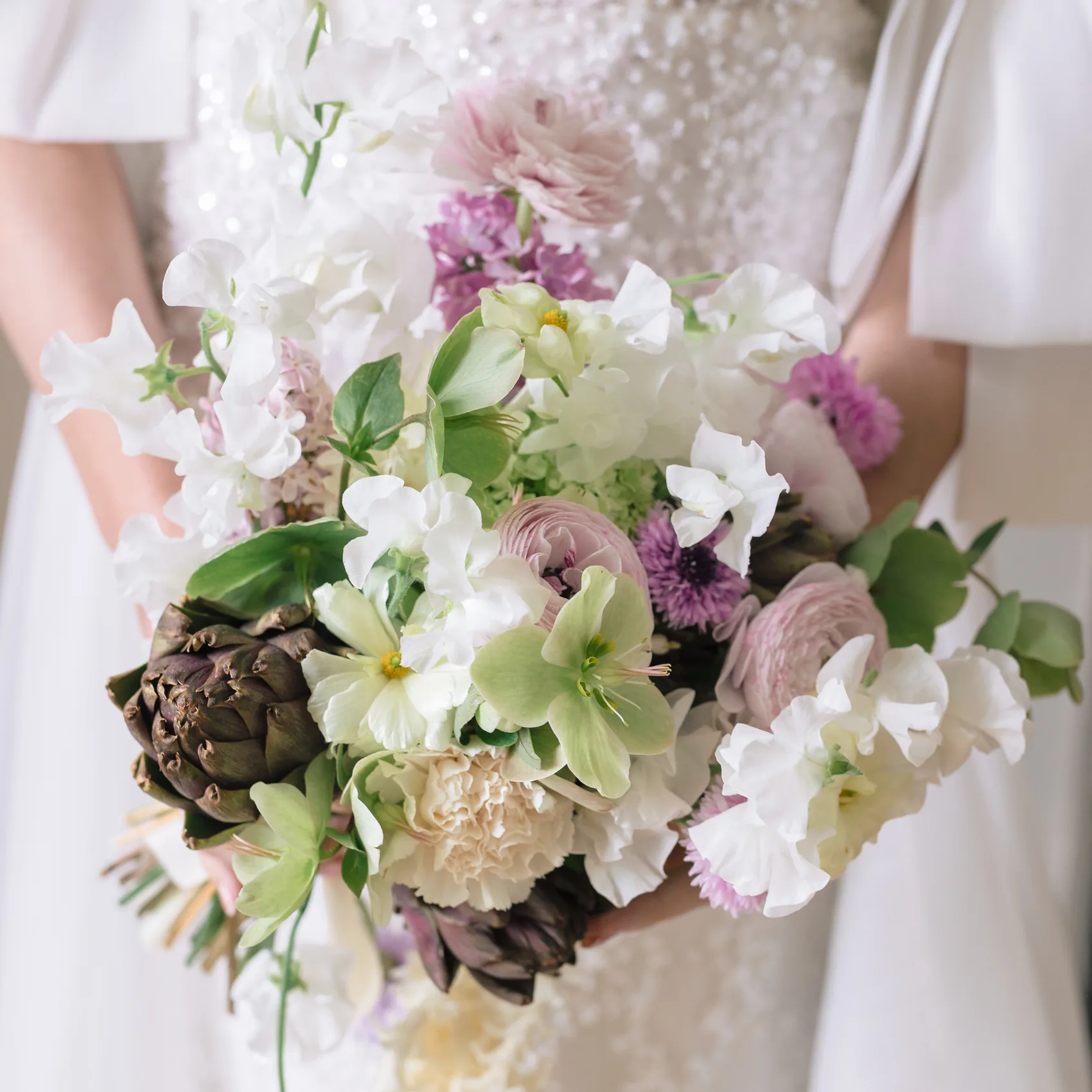 Bouquet de mariée composé de fleurs blanches et roses, tenu par la mariée
