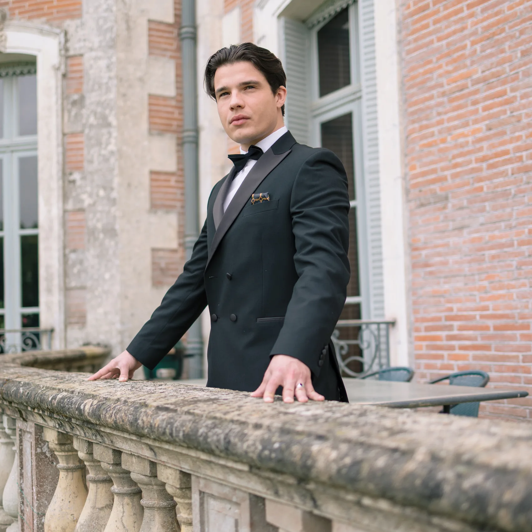 Portrait du marié en smoking, accoudé à une balustrade de pierre