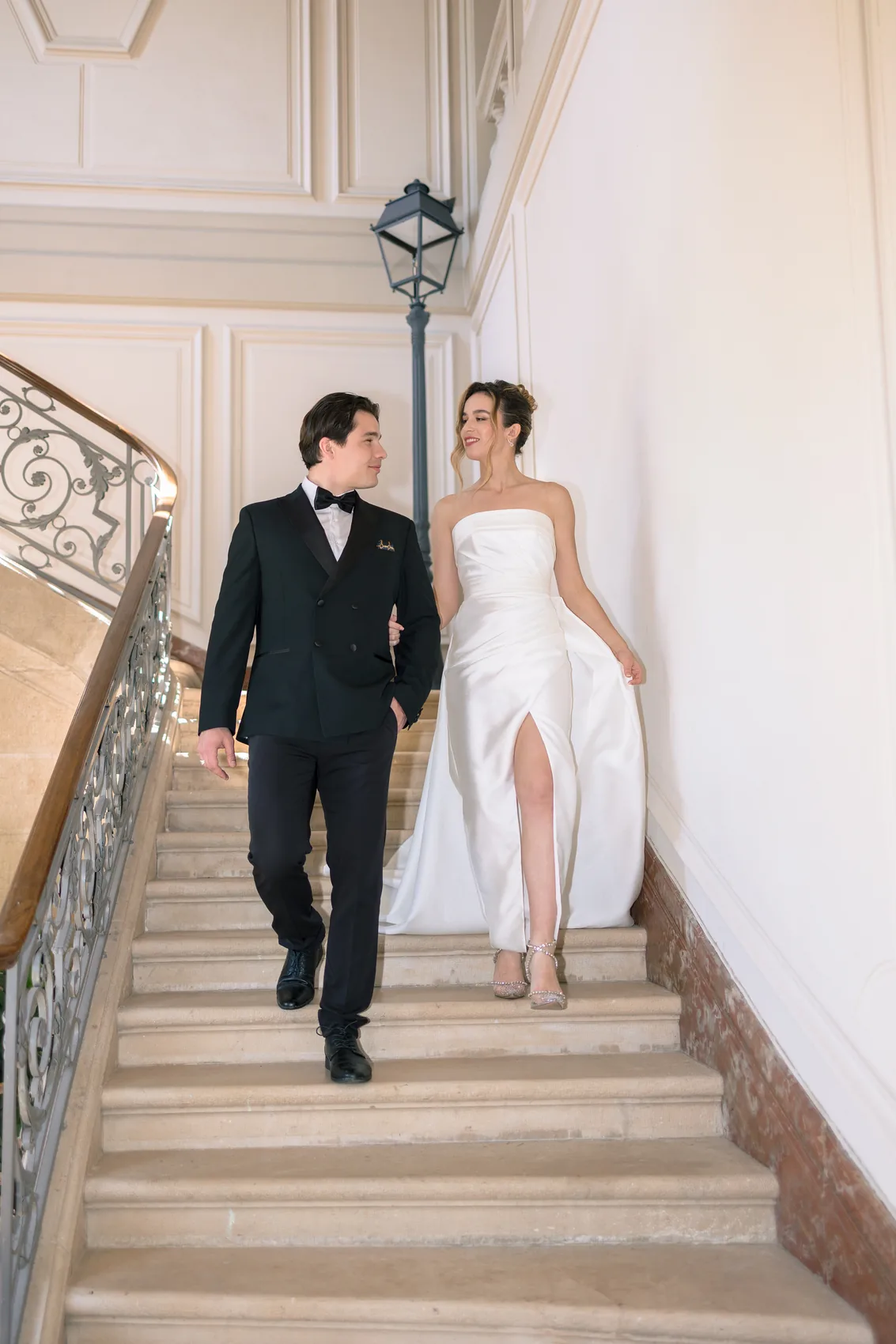 Les mariés montent un escalier intérieur, main dans la main