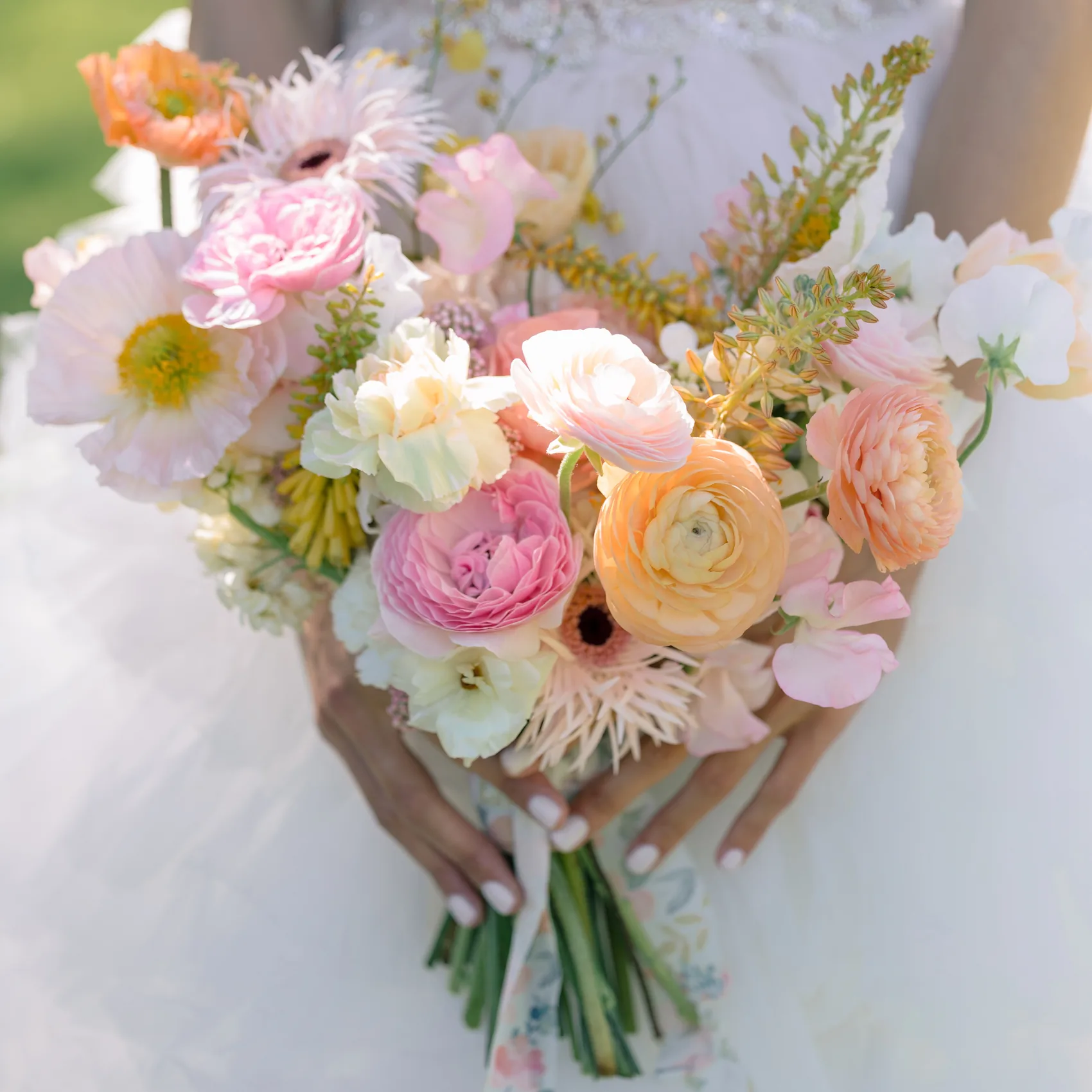 Gros plan sur un bouquet de renoncules et de pivoines tenu à deux mains