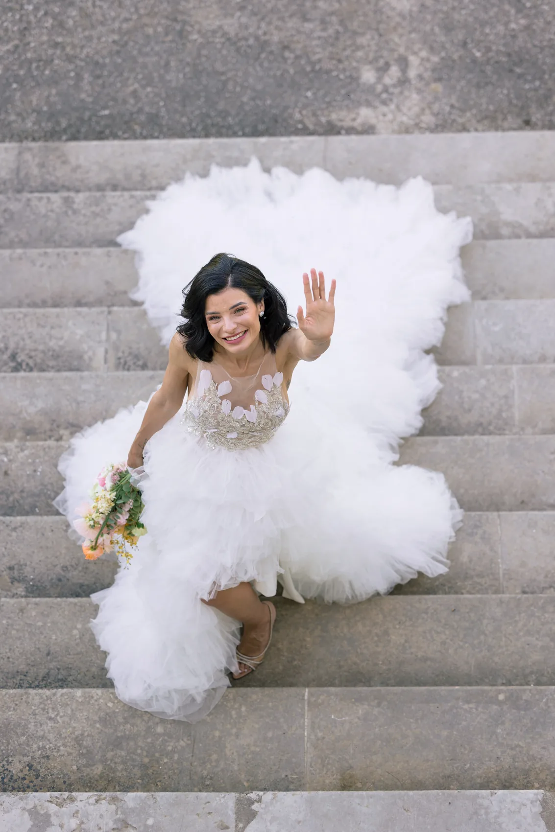 La mariée descend un escalier de pierre, robe de tulle courte