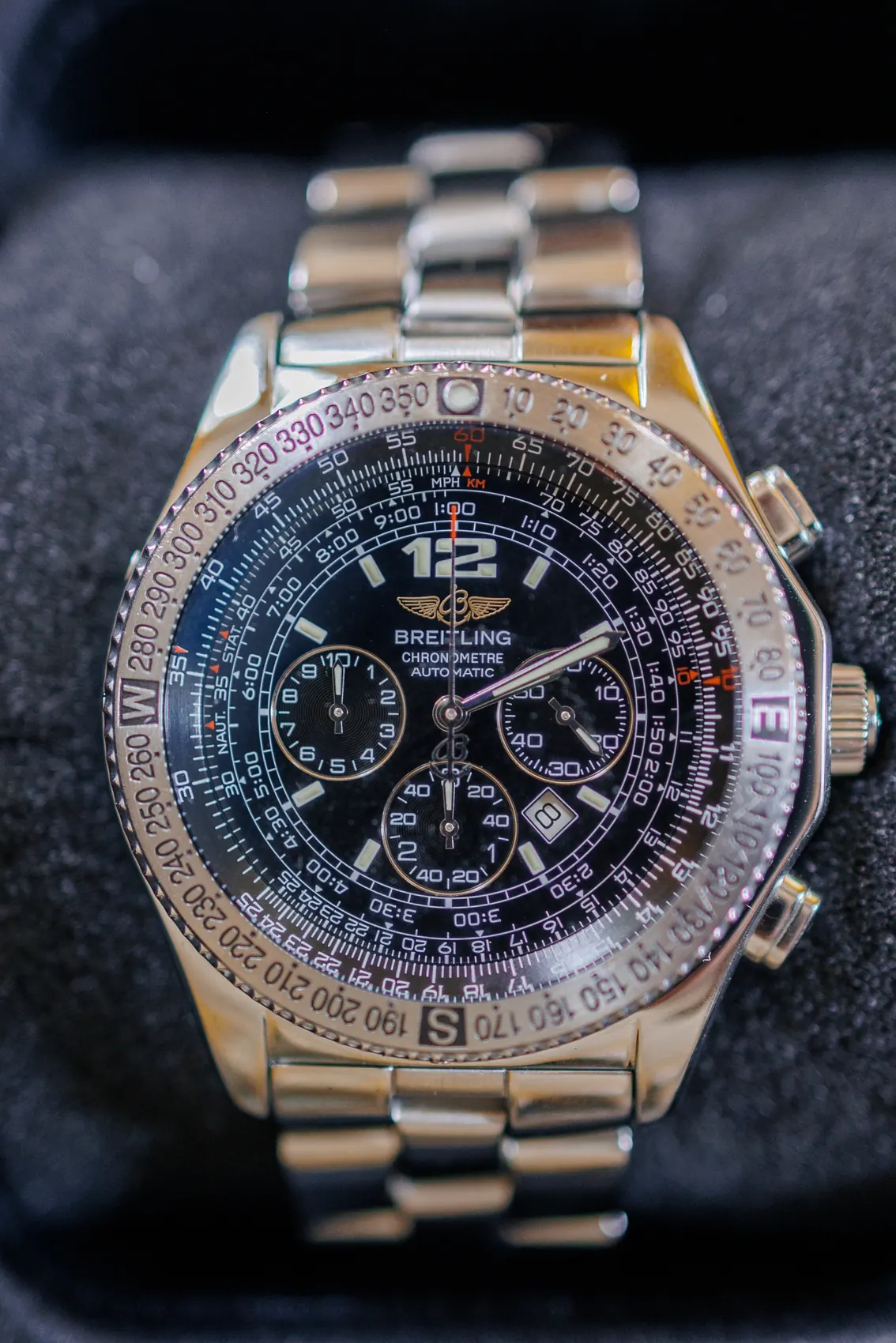 Montre chronographe du marié posée sur un tissu sombre
