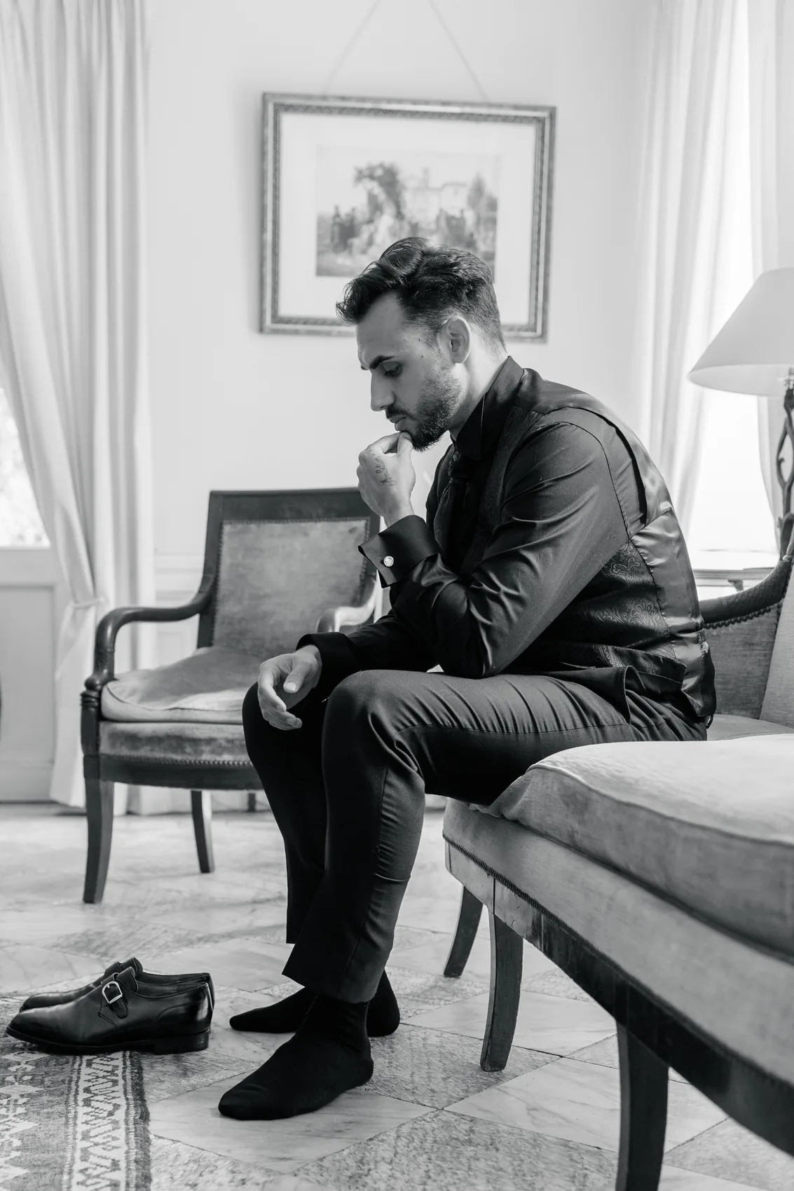 Le marié assis seul, tête baissée, avant la cérémonie, en noir et blanc