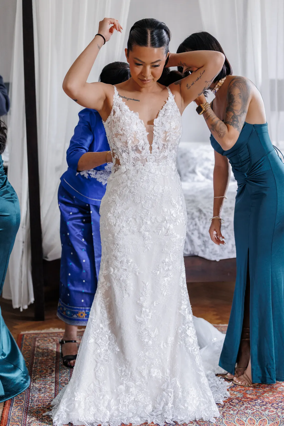 La mariée aidée par deux proches pour enfiler sa robe