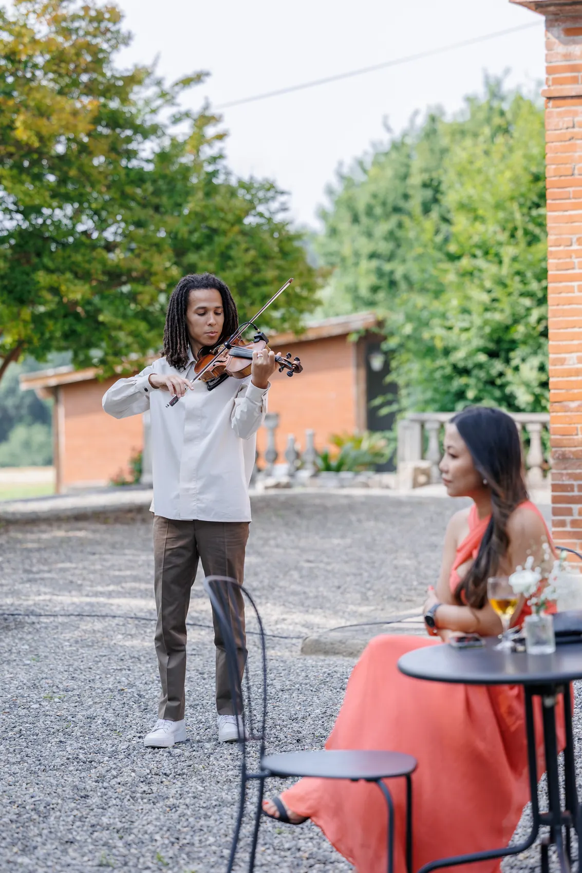 Un violoniste joue pendant le vin d'honneur, une invitée l'écoute attablée