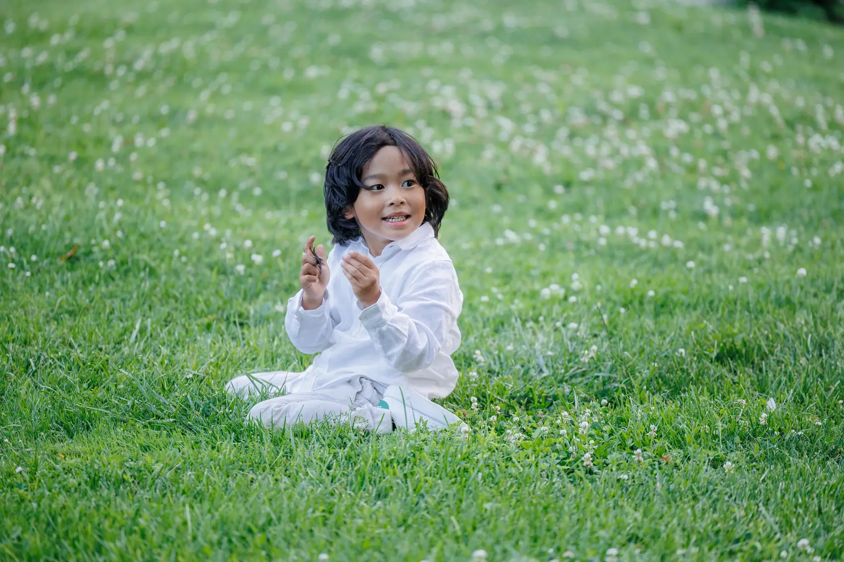 Un enfant assis dans l'herbe du parc pendant le vin d'honneur
