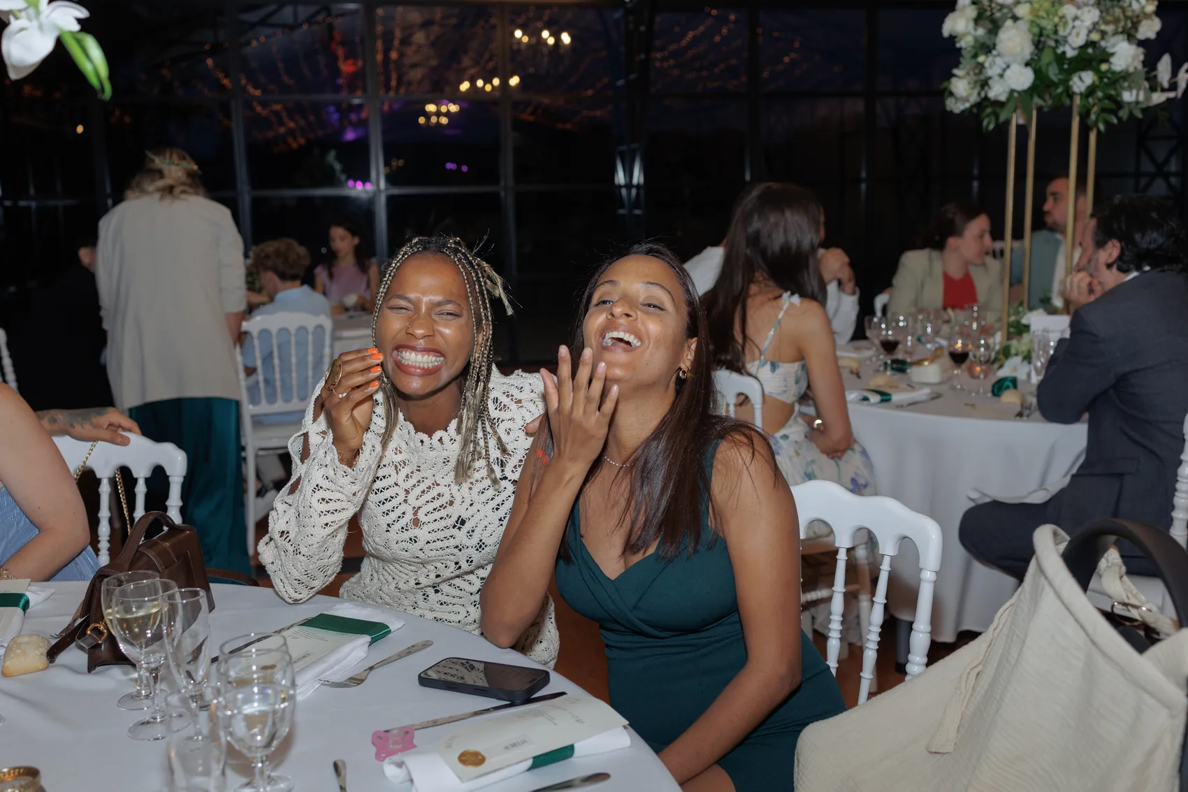 Deux invitées attablées éclatent de rire pendant le dîner